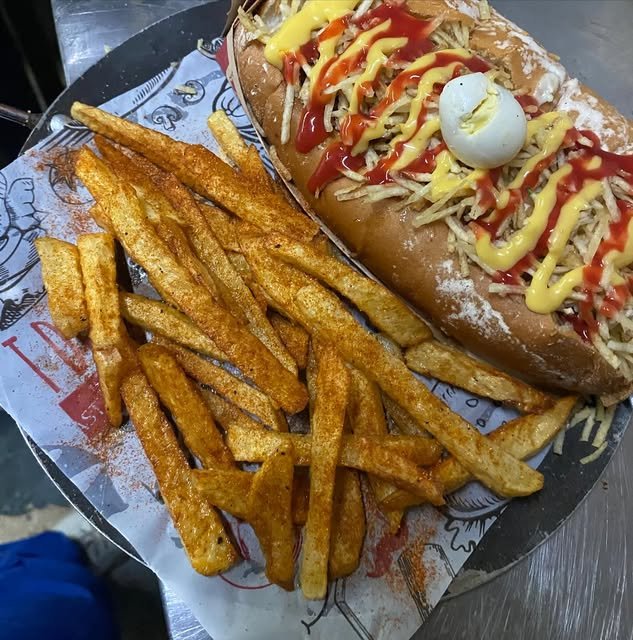 Perro caliente con salsas, huevo de codorniz y papas